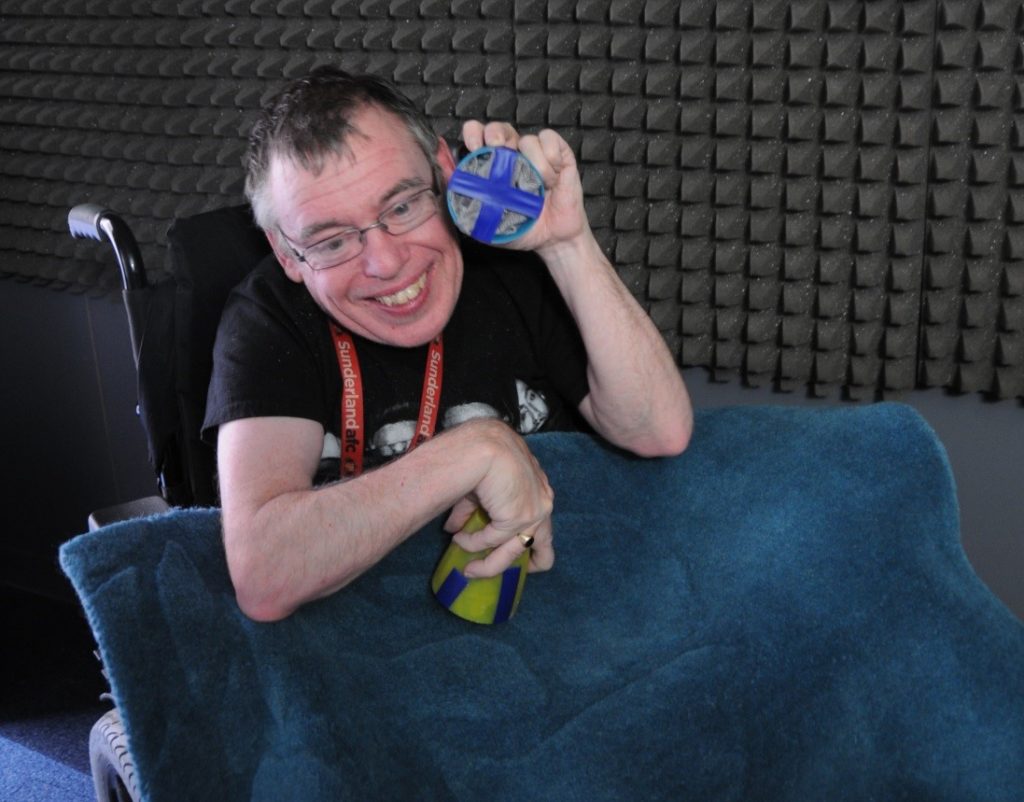 Daryn sitting in a sound studio producing background sounds for the book