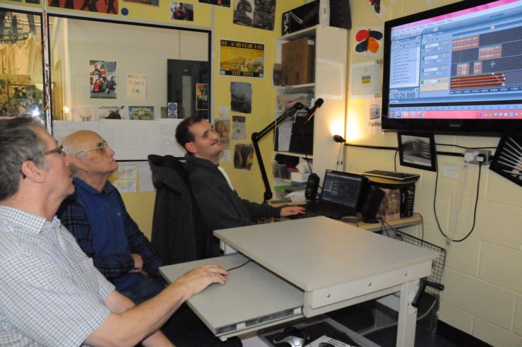 Trevor, Brian & Jamie sitting in front of a computer editing audio files