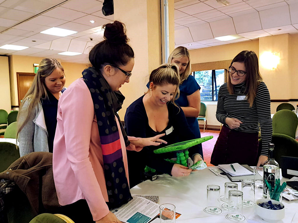 Group of delegates at the techability conference enjoying an iPad in a green protective case