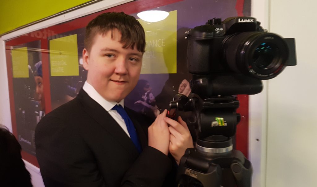 New Bridge student standing next to a video camera