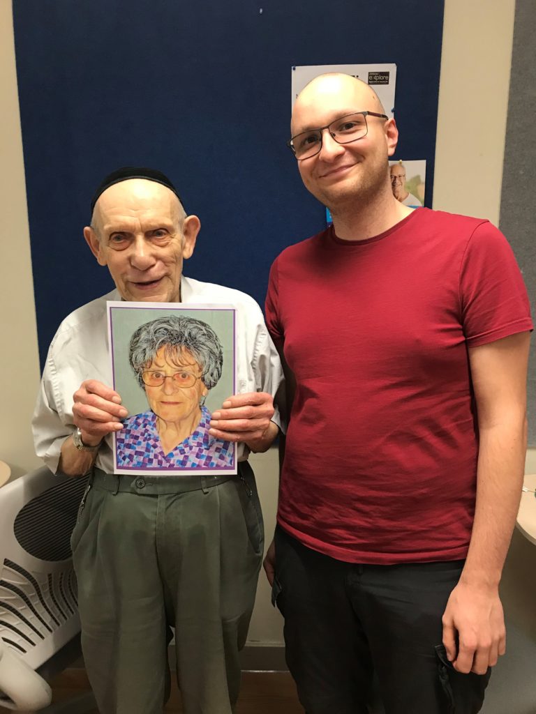 Justin and Philip holding up a printed photo of an elderly lady wearing glasses