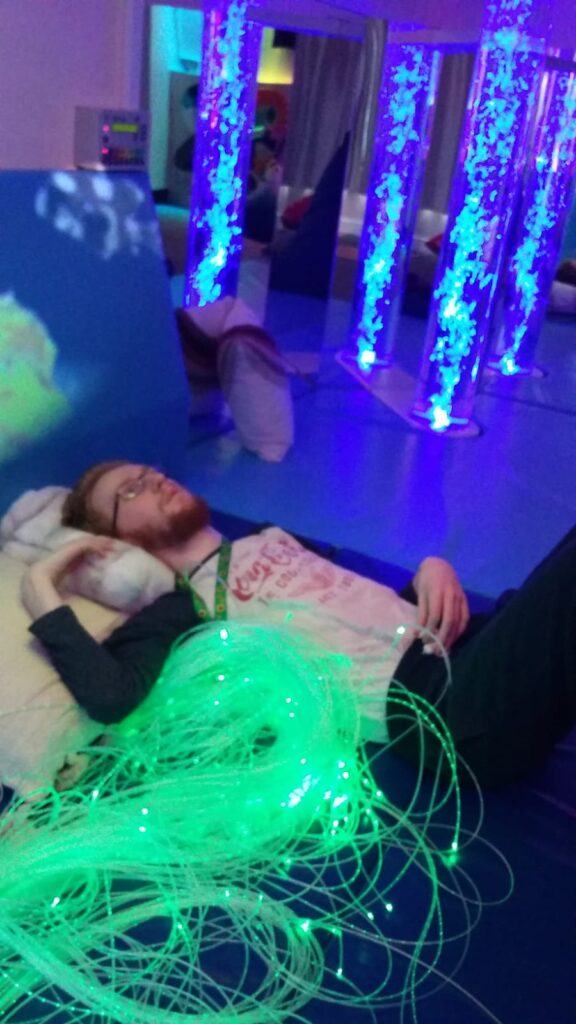 Person lying down next to the Interactive fibreoptic unit with the bubble tubes in the background  