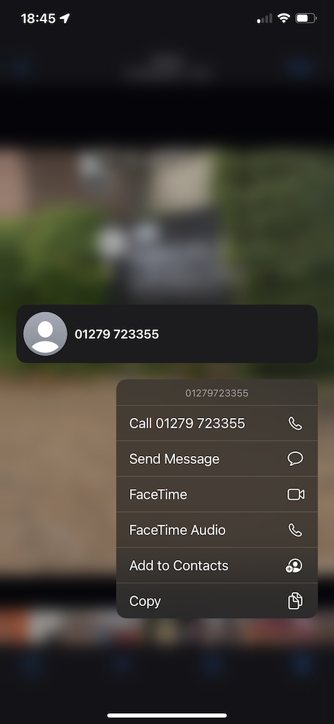 A screen shot showing a photo of a sign, logs for sale. A long press was performed on the phone number and a context menu with the options to call, or send a message to that number is now being shown.