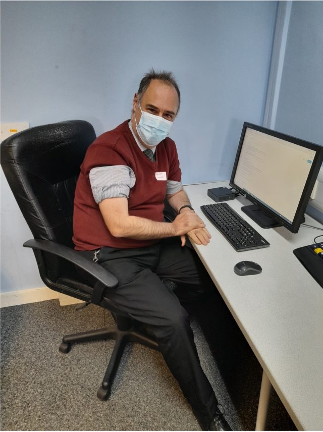 Matthew, sitting in front of a computer smiling