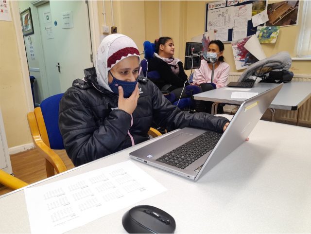 A lady sitting at a desk with a laptop in front of her 