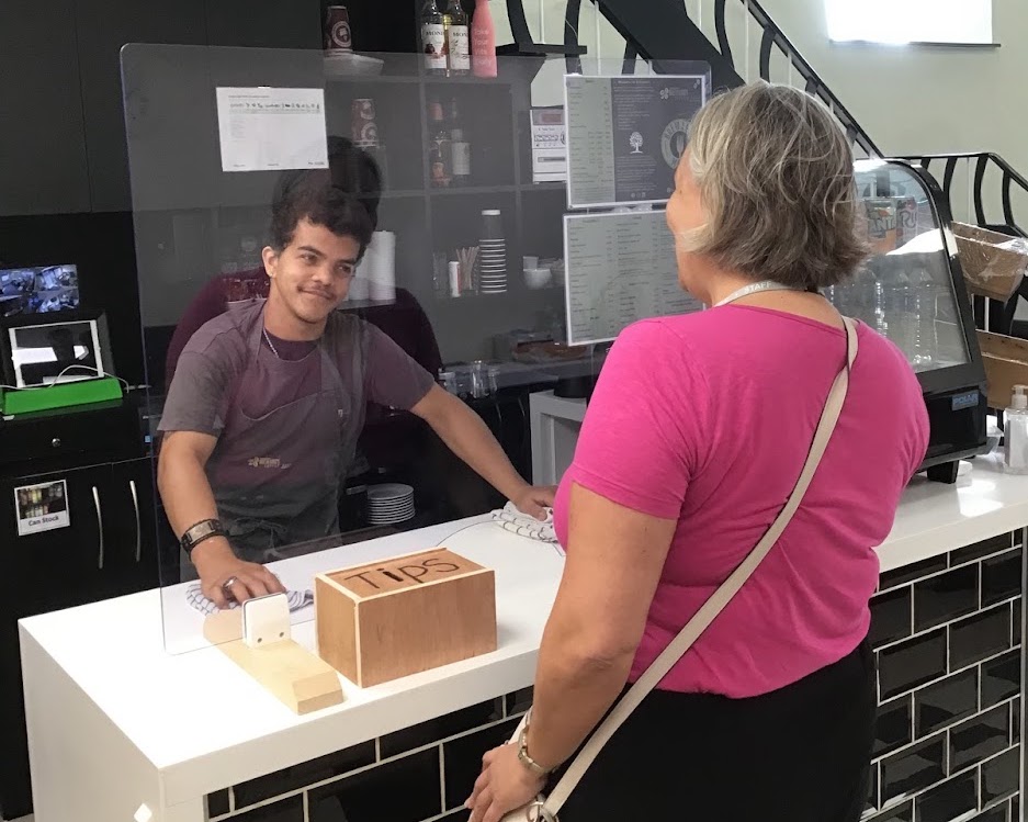 Homefield Student Jed working at Breward's coffee shop serving a customer. 