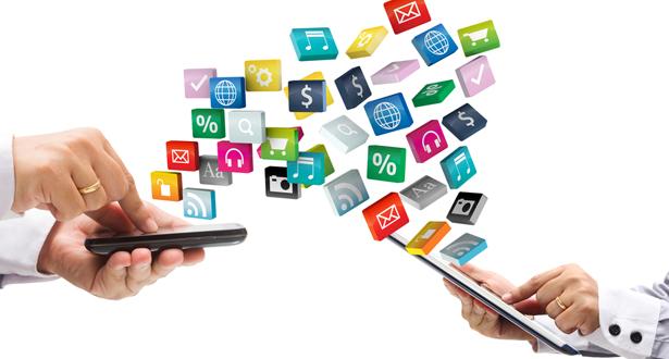 two people facing each other holding mobile devices, icons are shown in the air between them to represent file transfer between the devices 