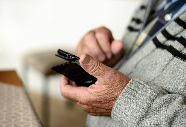 Elderly person holding and using a mobile phone
