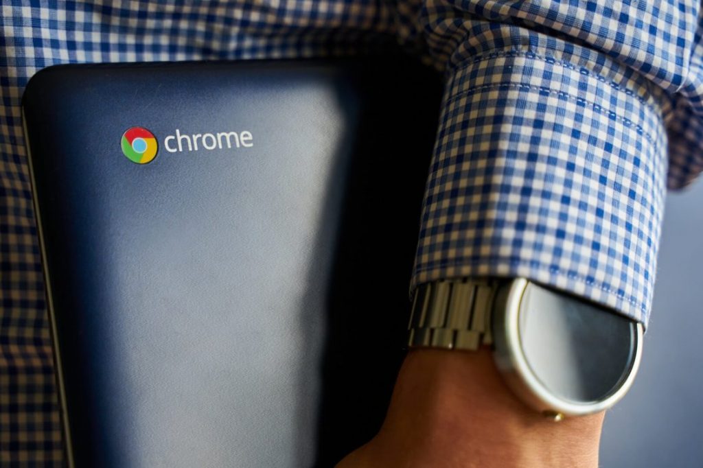 A man holding a Chromebook computer in his hand