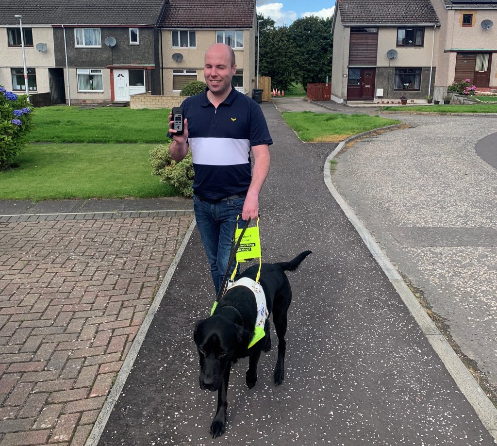 Stuart Beveridge walking with his guid dog, Dax. Stellar Trek GPS device in hand