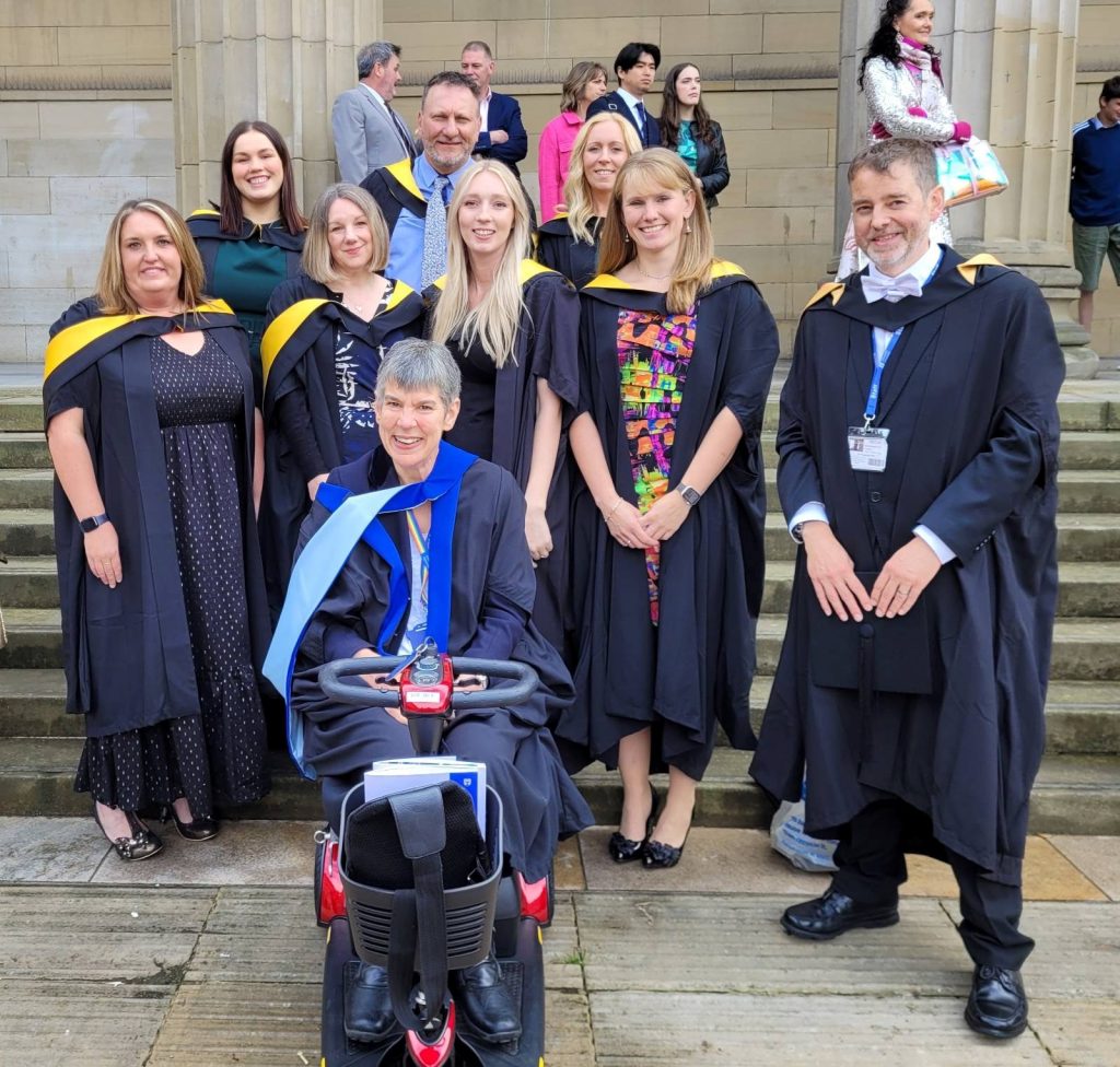 The second cohort of the Educational Assistive Technology course posed in graduation gowns on the Caird Hall steps
