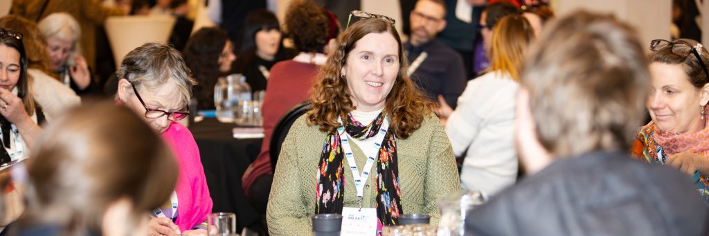 A TechAbility conference attendee smiles whilst participating in a group conversation.
