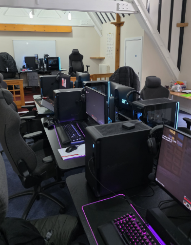 A computer lab with multiple gaming PCs, monitors, and gaming chairs arranged in rows for esports training.