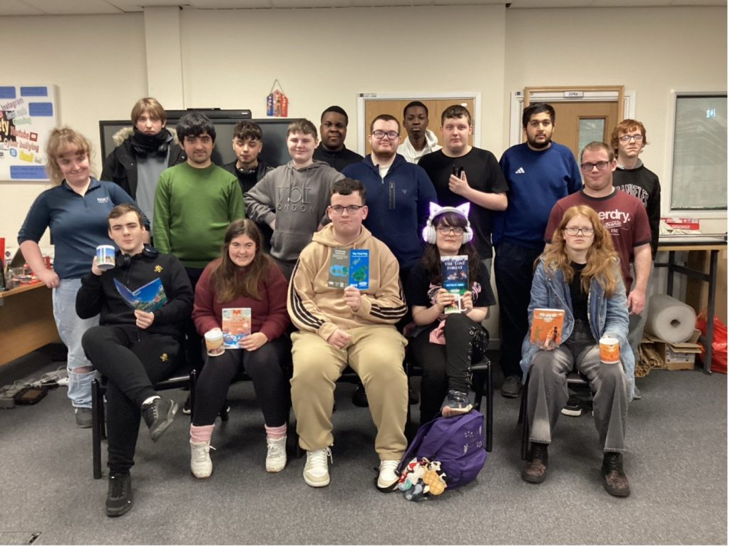 A group of approximately twelve students smiling for a team photo in a classroom or studio space. Several students are holding copies of Wonder books. The image is the Wonder student publishing team.